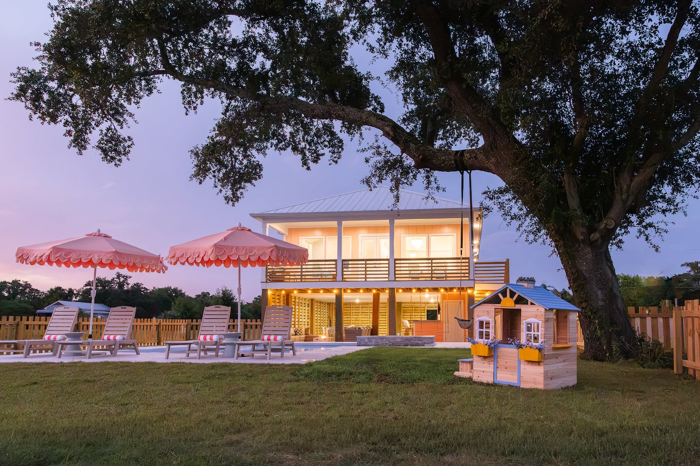 Peach-colored home at dusk beneath the backyard live oak